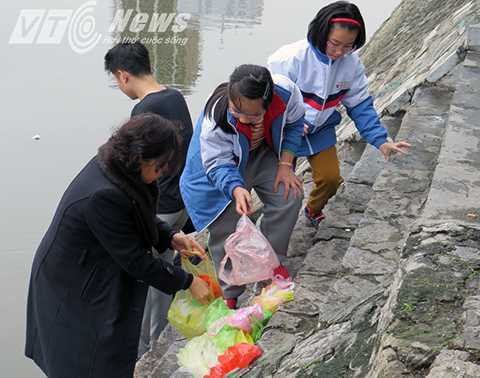 Bà giáo già dẫn một tốp học sinh tiểu học ra thả cá, đồng thời hướng dẫn các cháu nhặt túi nilon bỏ vào thúc rác thay người lớn