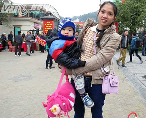 Người mẹ trẻ tay sách nách mang cùng chồng, con hồi hộp chờ đến giờ xuất phát về quê ăn Tết