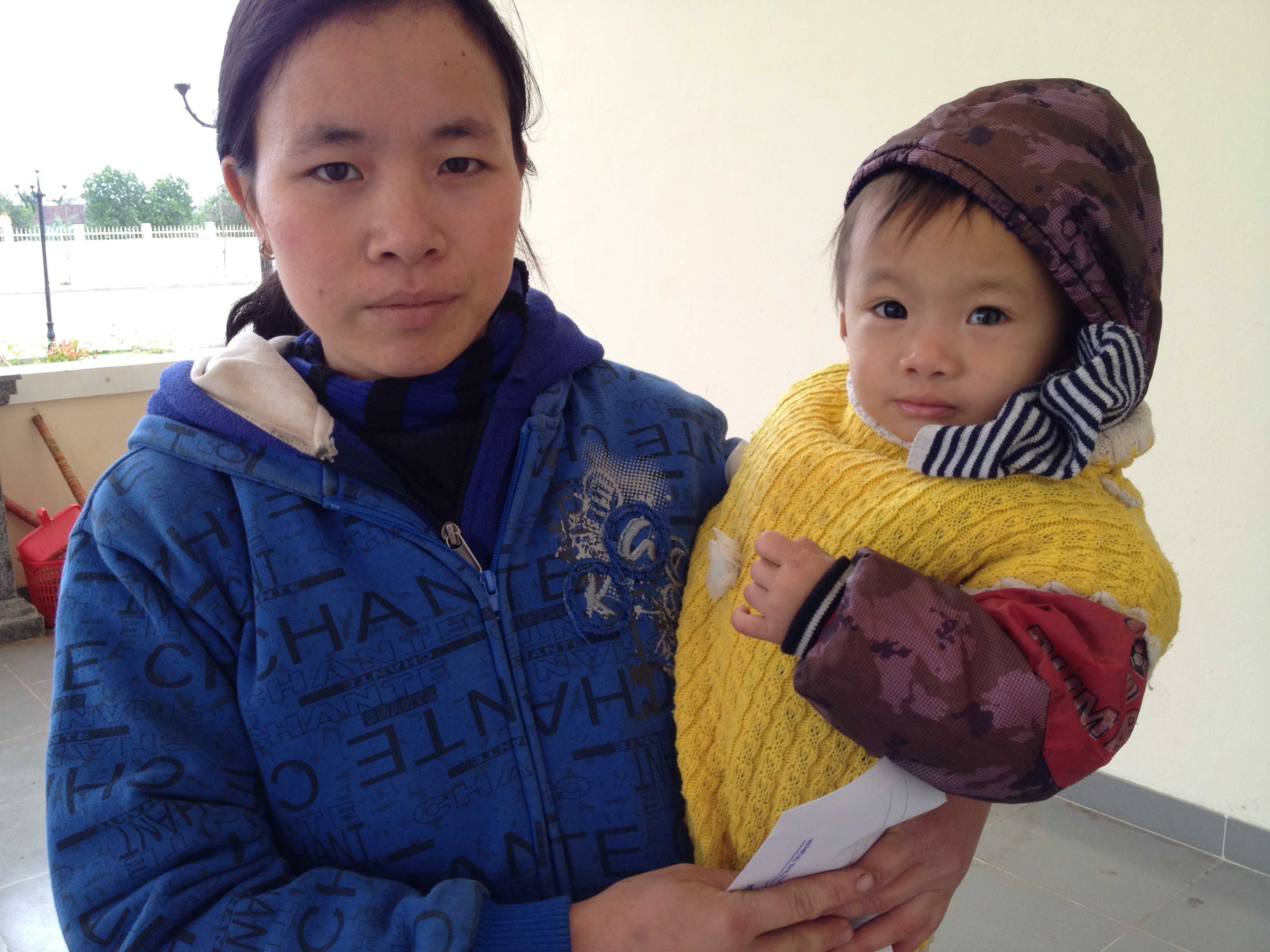 Chị Trần Thị Hằng (xã Quang Thiện, huyện Kim Sơn) bế con 2 tuổi đến nhận quà của Tập đoàn Indevco