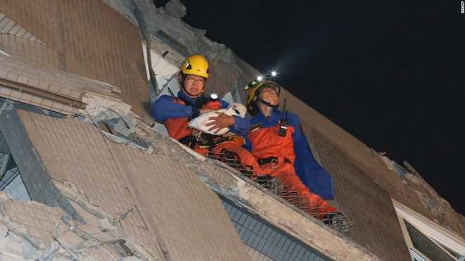 Đội cứu hộ bế một em bé ra khỏi hiện trường vụ sập chung cư do động đất. Đến 8h30 (giờ Hà Nội), một lính cứu hỏa cho biết anh và các đồng nghiệp đã giúp đưa hơn 100 người ra ngoài an toàn. Sở Cứu hỏa Đài Nam cho biết những người này đã được đưa đến các bệnh viện để điều trị vết thương. Ảnh: Reuters