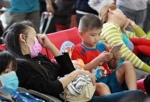 Để tranh kẹt xe, nhiều người tranh thủ ra sớm phải ngồi vật vạ trên ghế chờ Bến xe miền Đông. Trong ảnh, người mẹ và người dì ngủ gục bên đống valy mặc con chơi điện thoại.