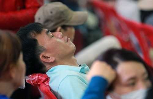 Người đàn ông sau khi giao đống đồ cho vợ coi cũng tranh thủ ngả đầu ra ghế ngủ tạm trong lúc chờ xe.