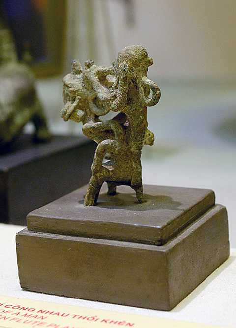 Tượng hai người cõng nhau thổi khèn thuộc nền văn hóa Đông Sơn, có niên đại khoảng 2.000-2.500 năm. Người cõng trong tư thế cong lưng, hai chân nhún nhảy, hai chân choàng ra ôm lấy người ngồi trên lưng. Tóc người cõng được búi cao, tai đeo khuyên tròn, rủ xuống ngang vai. Người ngồi lên lưng miệng ngậm khèn, một tay ôm lấy người cõng, một tay đỡ khèn. Đây là tiêu bản hiếm hoi về nghệ thuật tượng tròn thời Đông Sơn, phản ánh sinh động một khía cạnh của xã hội phát triển về mọi mặt, đặc biệt là âm nhạc truyền thống. Hình thức sinh hoạt âm nhạc ấy đến nay vẫn còn đọng lại ở nhiều dân tộc thiểu số. Tượng hai người cõng nhau thổi khèn thuộc nền văn hóa Đông Sơn, có niên đại khoảng 2.000-2.500 năm. Người cõng trong tư thế cong lưng, hai chân nhún nhảy, hai chân choàng ra ôm lấy người ngồi trên lưng. Tóc người cõng được búi cao, tai đeo khuyên tròn, rủ xuống ngang vai. Người ngồi lên lưng miệng ngậm khèn, một tay ôm lấy người cõng, một tay đỡ khèn. Đây là tiêu bản hiếm hoi về nghệ thuật tượng tròn thời Đông Sơn, phản ánh sinh động một khía cạnh của <a href='https://vtcnews.vn/xa-hoi.2.0.html' >xã hội</a> phát triển về mọi mặt, đặc biệt là âm nhạc truyền thống. Hình thức sinh hoạt âm nhạc ấy đến nay vẫn còn đọng lại ở nhiều dân tộc thiểu số.