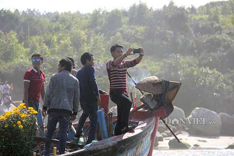 Người trên bờ và đi trên thuyền sử dụng điện thoại ghi lại khoảnh khắc của buổi lễ.