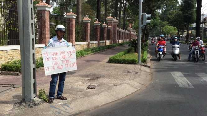 Anh Điền với tấm bảng xin lỗi cảnh sát giao thông trên đường Nguyễn Đình Chiểu, Q.3, TP.HCM sáng 12-2 - Ảnh: Lê Hồng Thảo