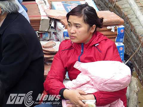 Bế con ngồi chờ nhìn dòng người la hét