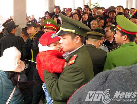 Chiến sỹ Công an bế cháu bé thoát khỏi dòng người chen lấn để được ưu tiên đi trước