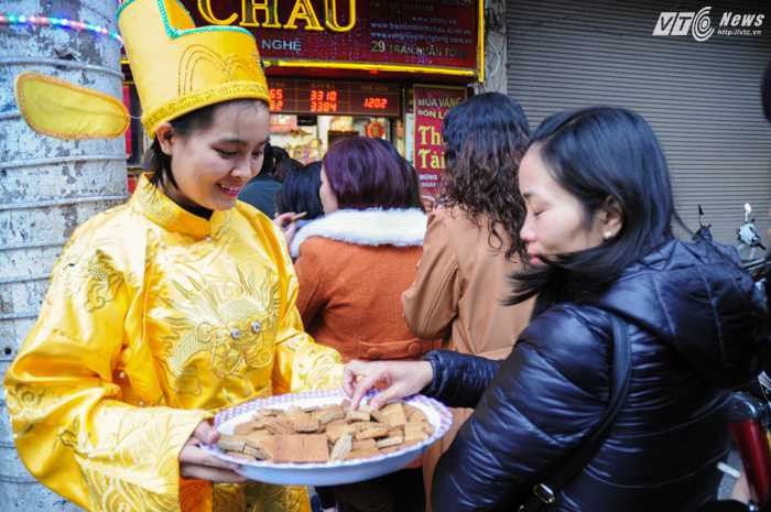 Nhân viên các cửa hàng hóa trang thành thần tài phục vụ khách mua trong lúc chờ đợi - Ảnh: Tùng Đinh