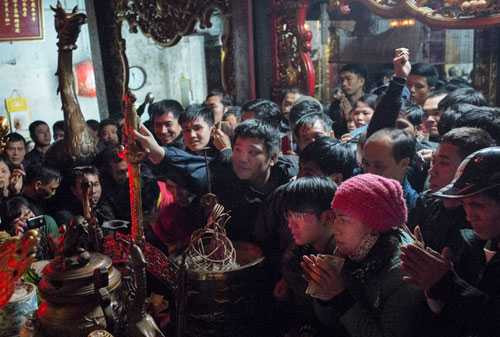 Người dân chen nhau, cố với tay thật xa để quẹt tiền hoặc chạm được thanh kiếm linh thiêng ở trong hậu cung trong lễ khai ấn năm 2015.