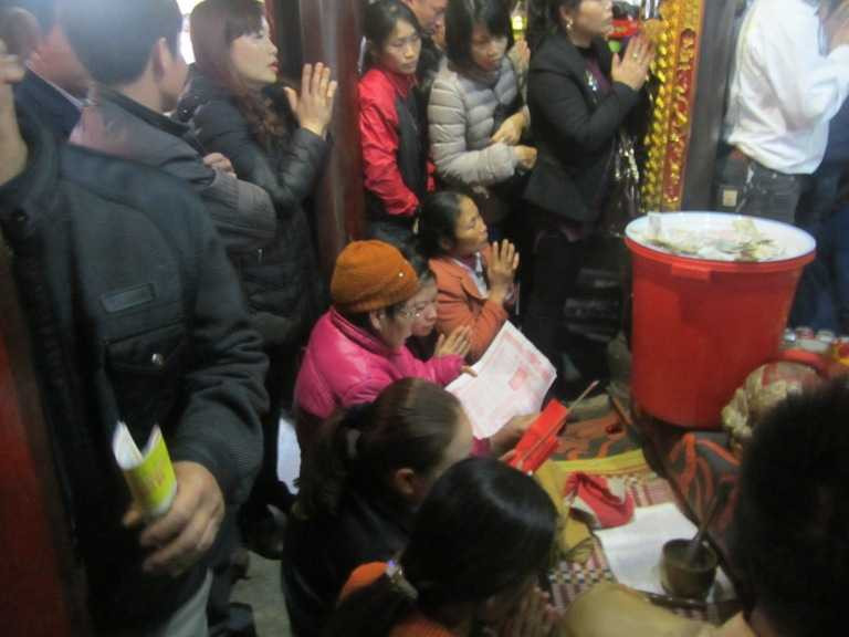 Ở vị trí trung tâm, người phụ nữ mặc áo hồng đang ra sức khấn thuê cho các gia chủ.