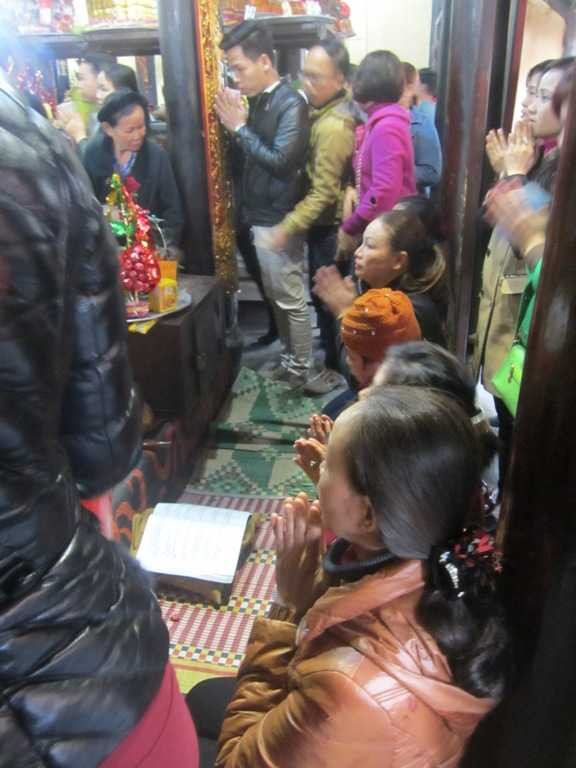 Ở một vị trí trung tâm khác, các đối tượng khấn thuê sử dụng quyển sổ khấn và ngồi hàng giờ liền trong điện thờ