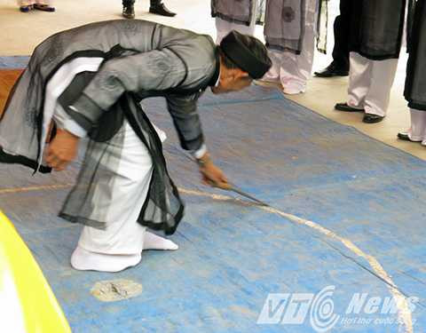 Ông Trưởng thôn cầm dao bầu thực hiện nghi thức chỉ trời, vạch đất, sau đó dùng con dao này cắt tiết gà