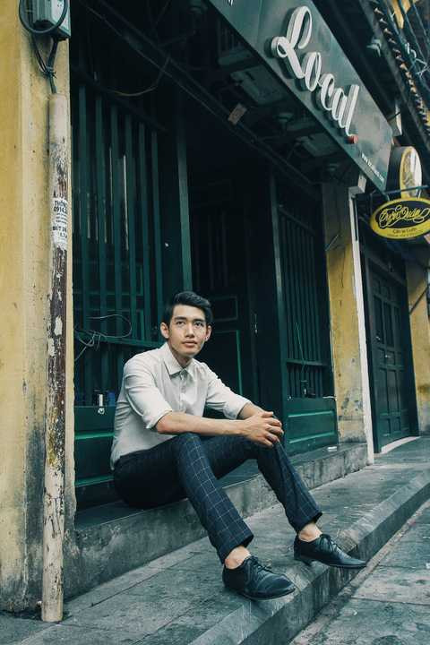 Quang Đăng cũng tranh thủ ghi lại những hình ảnh tại Hà Nội xinh đẹp. Trong không gian có phần cũ kĩ của những dãy nhà xưa cổ, chàng vũ công diệnmột set đồ mang phong cách vintage với áo sơ mi trắng độc mộc kết hợp chiếc quần tây caro xanh rêu và không quên kèm theo một đôi giày tây đen không cầu kì.