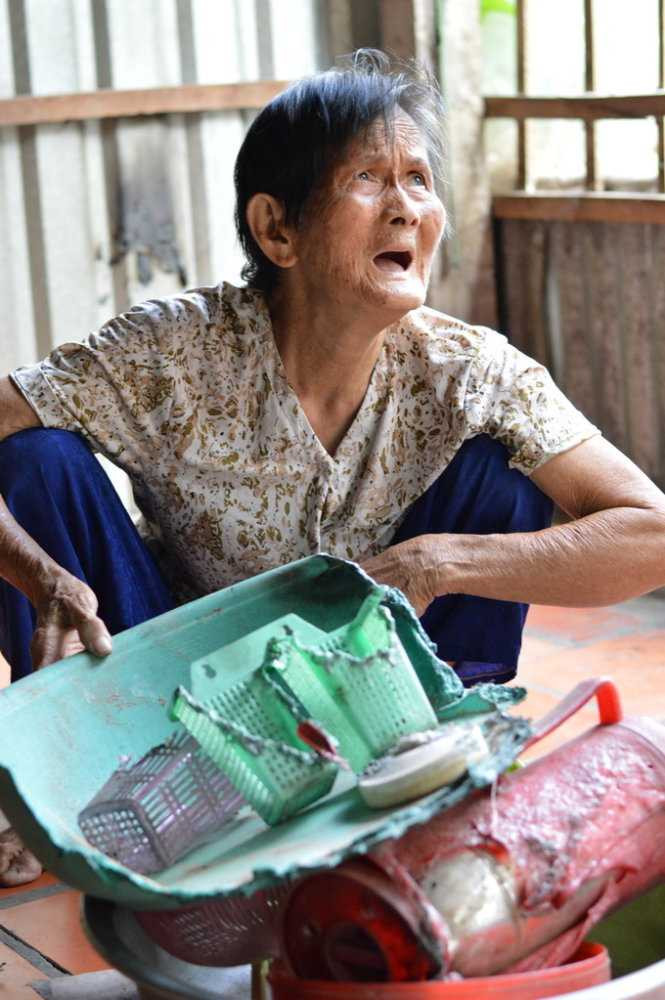 Bà Cỏi bên các vật dụng bị đốt cháy - Ảnh: Ngọc Tài