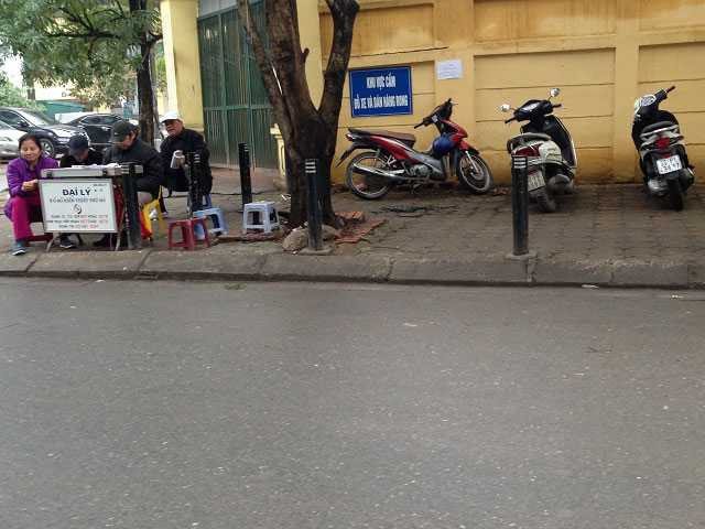 Khu vực trường Trung học phổ thông Cầu Giấy (phố Nguyễn Khánh Toàn) mặc dù đã lắp biển “cấm đỗ xe, bán hàng rong” song người dân xung quanh vẫn bất chấp để xe trên vỉa hè và ngồi bán vé số. (Ảnh chụp tháng 1/2016).