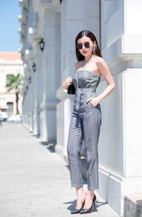 Cô khoe thềm ngực gợi cảm với jumsuit dạng quây, để bộ cánh hài hoà hơn cô sử dụng mắt kính bản to đi kèm clutch cầm tay.