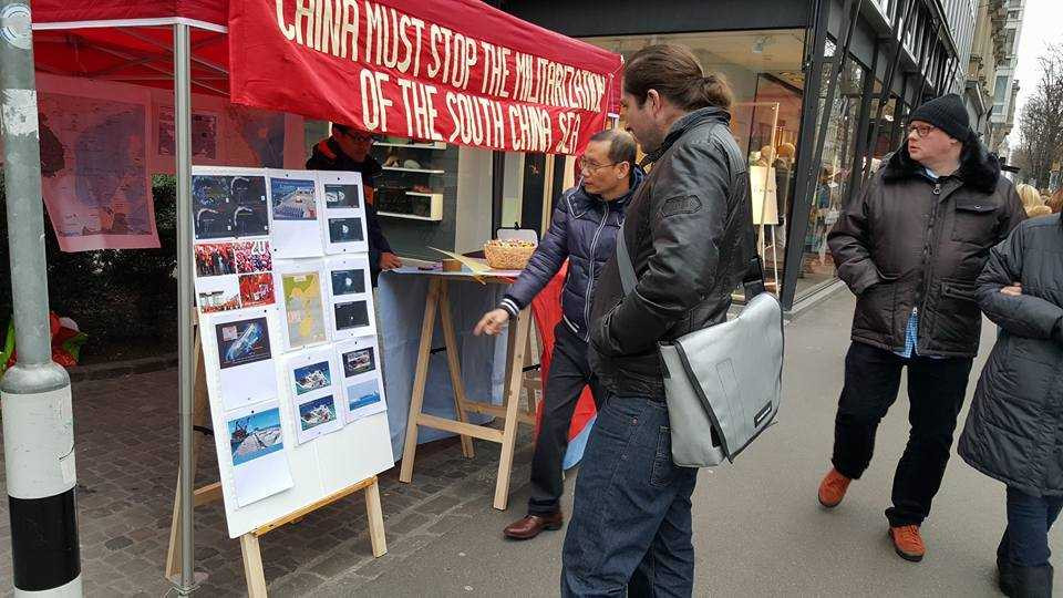 Anh Nguyễn Văn Thái đang chỉ cho 1 thanh niên Thụy Sĩ những hình ảnh về việc xây dựng trái phép và quá trình quân sự hoá gần đây của Trung Quốc trên các hòn đảo chiếm đóng của Việt Nam