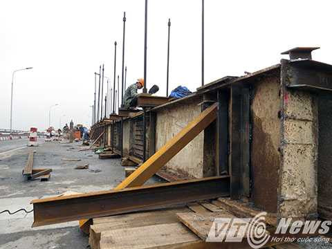 Một thanh dầm thép chữ I dài 30m được đặt trên mặt cầu leo giữ mặt để tháo lắp thành dầm bị hỏng phía dưới Một thanh dầm thép chữ I dài 30m được đặt trên mặt cầu leo giữ mặt để tháo lắp thành dầm bị hỏng phía dưới