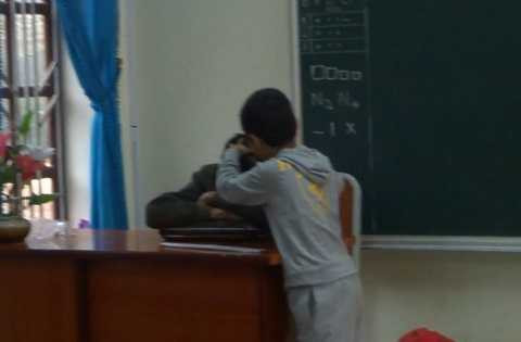 Hình ảnh thầy giáo nằm gục trên bàn để học sinh nhổ tóc bạc - Ảnh cắt từ clip 