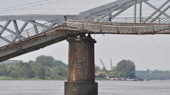 Chiếc sà lan va vào móng cầu khiến 2 nhịp cầu bị gãy. Ít nhất 3 người đang chạy xe máy trên cầu rớt xuống sông, tuy nhiên tất cả đã được cứu kịp thời. (Ảnh: Bạn đọc Nguyen Trong Hieu/TTO)