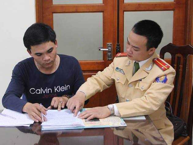 Tài xế Diệp (trái) ký vào biên bản xử phạt