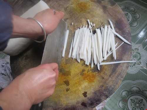 Chị Nghi phải dùng hết sức mới thái được bánh đá Chị Nghi phải dùng hết sức mới thái được bánh đá