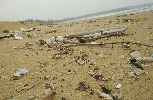 Dầu vón cục lẫn trong rác dạt vào bờ biển