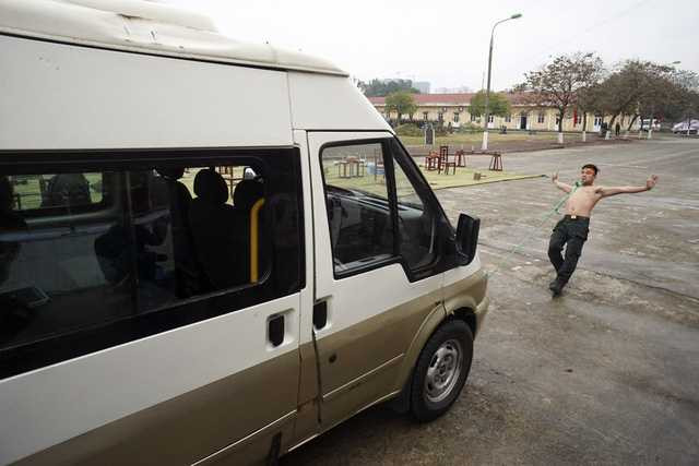 Một chiến sỹ dùng răng kéo chiếc xe ô tô chở khách.