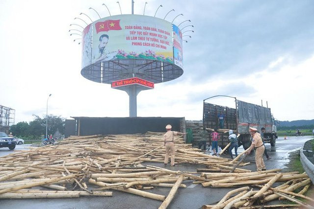 Hai chiến sĩ CSGT cùng một số người dân phụ giúp tài xế bốc gỗ keo lên xe.