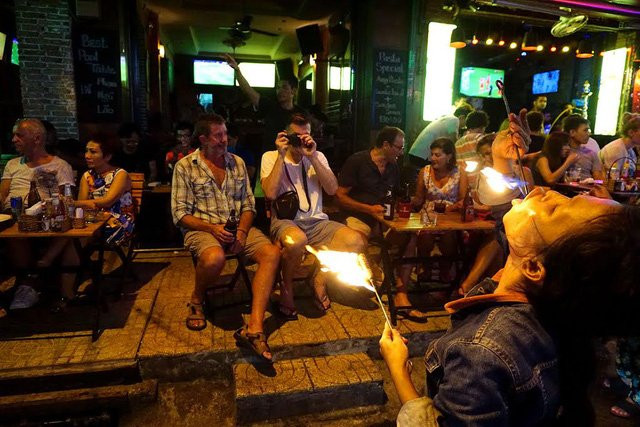 Những người nước ngoài tò mò, dùng máy ảnh ghi lại cảnh chị Sen nuốt lửa.