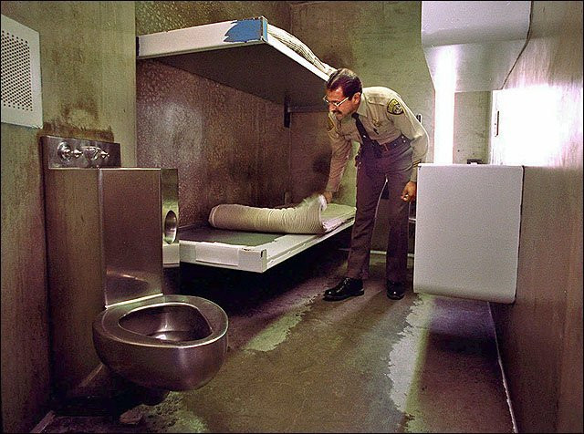 ...Correctional officer Michael Melo searches a high-security cell at Corcoran State Prison in this June 25, 1996, file photo. Each cell contains a bed, sink, desk and toilet-ap-scottanger 3