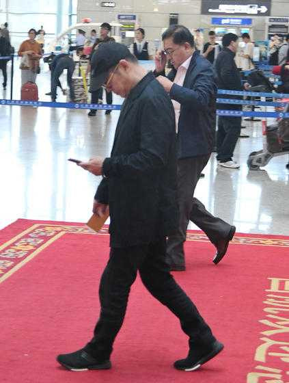 Trong khi paparazzi săm soi, Lý Liên Kiệt cắm cúi nhìn điện thoại.