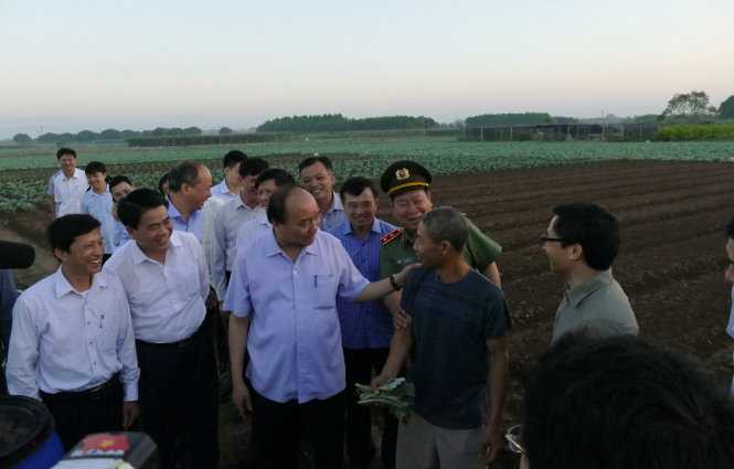 Rời chợ Long Biên lúc 5g30, Thủ tướng đã qua cầu Chương Dương đến cánh đồng rau của xã Văn Đức, huyện Gia Lâm và yêu cầu lái xe chạy thẳng ra bờ ruộng. Lúc này mới tờ mờ sáng, chỉ bắt gặp vài người dân đi làm đồng sớm, Thủ tướng hỏi anh Tới - một nông dân về quy trình làm rau sạch, các loại thuốc bảo vệ thực vật và phân bón mà nông dân này sử dụng - Ảnh: LÊ KIÊN