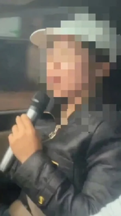 Nữ tài xế một tay cầm micro hát karaoke, một tay lái xe ô tô