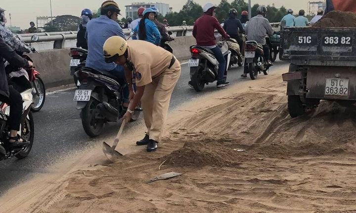 CSGT cặm cụi dọn đất cát trên cầu vượt ở TP.HCM