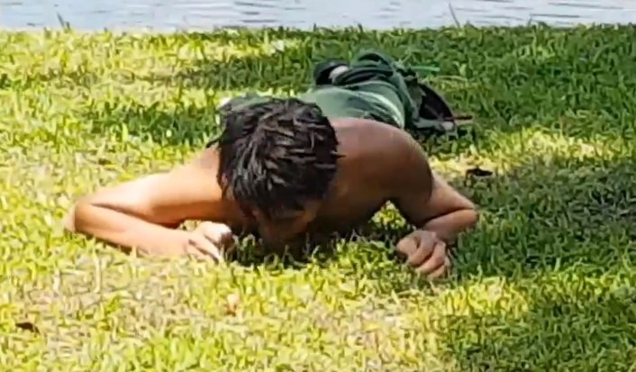 Nam thanh niên nằm gặm cỏ giữa trưa nắng ở ven hồ Hà Nội