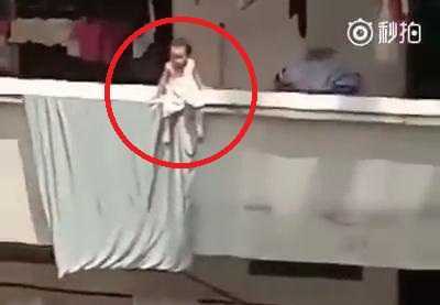 Thót tim nhìn bé gái ngồi vắt vẻo trên ban công nhà cao tầng sưởi nắng