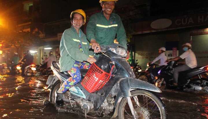 TP.HCM: Chồng còng lưng đẩy vợ vượt triều cường