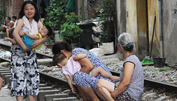 Thản nhiên bế cháu ngồi trên đường ray tán gẫu, thách thức tử thần