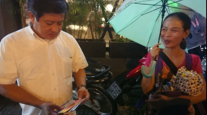 Ông Đoàn Ngọc Hải mua hết vé số cho người phụ nữ ẵm con nhỏ đi bán dưới mưa
