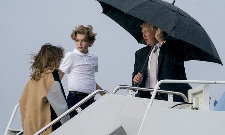 Tổng thống Trump che ô một mình, để vợ con đội mưa lên máy bay