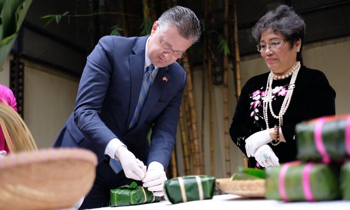 Đại sứ Mỹ Daniel Kritenbrink hào hứng học gói và cắt bánh chưng bằng lạt
