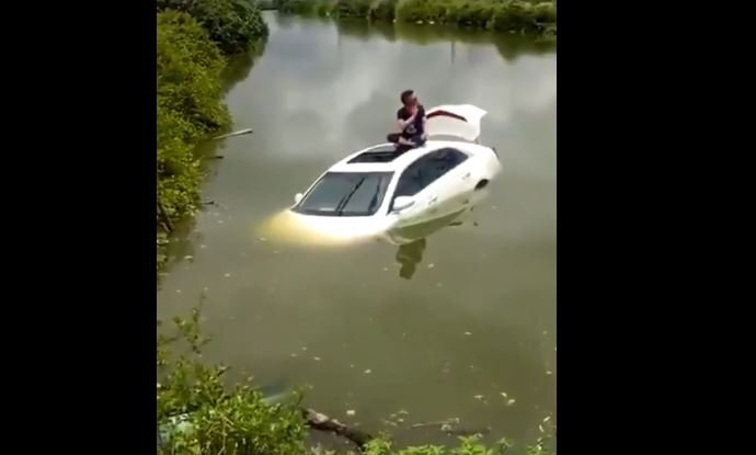 Tài xế khoanh chân ngồi trên nóc ôtô ngập nước chờ cứu hộ