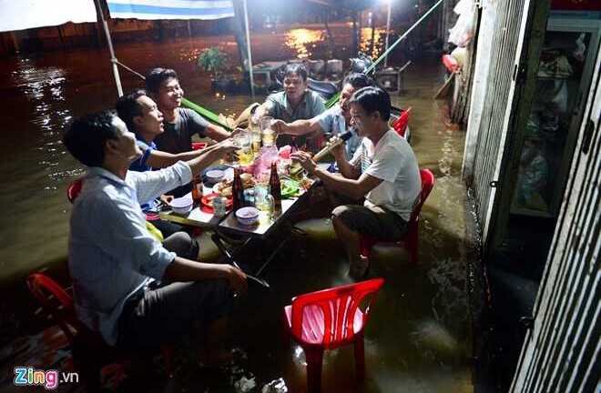Ảnh: Kẻ tát nước, người ngồi nhậu trên dòng nước triều cường