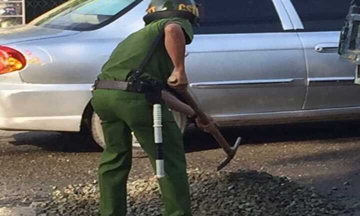 Cảnh sát trật tự mua đá dăm lấp ổ gà tránh tai nạn cho dân