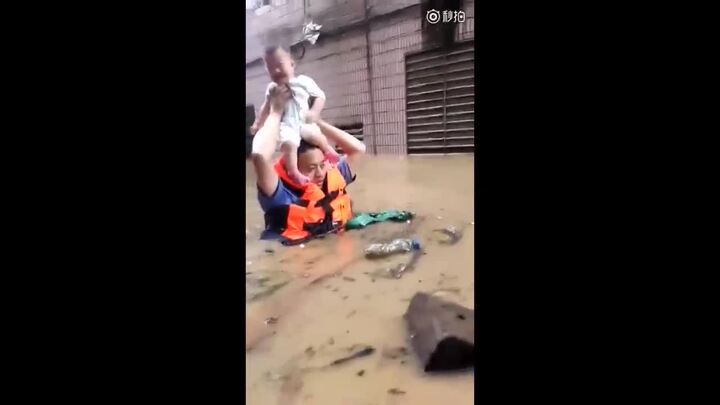 Nước dâng đến ngực, cảnh sát cho em bé ngồi lên đầu vượt đường ngập