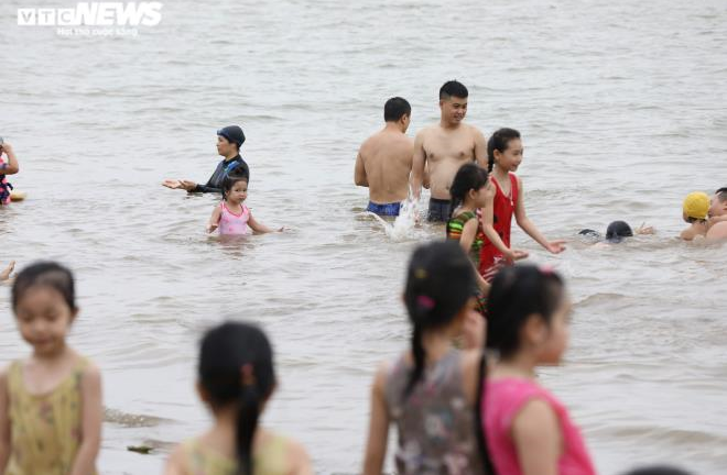 Hàng trăm người đổ ra bãi cát ven sông Hồng tắm giải nhiệt, bất chấp biển cấm