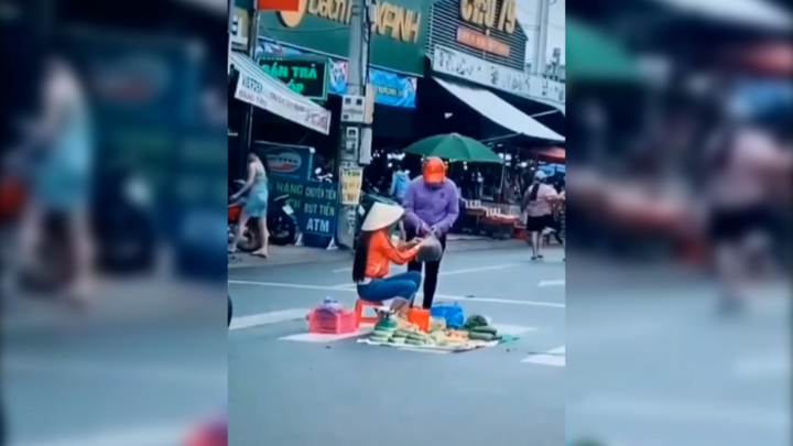 Người phụ nữ ngồi bán trái cây giữa lòng đường mặc xe cộ qua lại tại Bình Dương