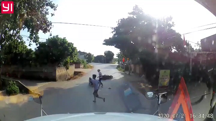 Tránh trẻ chạy sang đường, 2 người đi xe máy ngã dúi dụi trước container