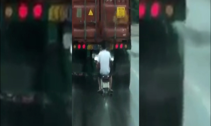 Clip: Người đàn ông đi xe máy cố tình bám đuôi container để tránh mưa